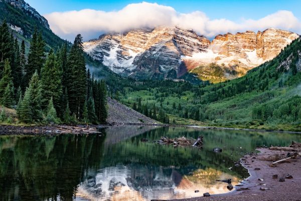 green pine trees near lake and snow covered mountain during daytime